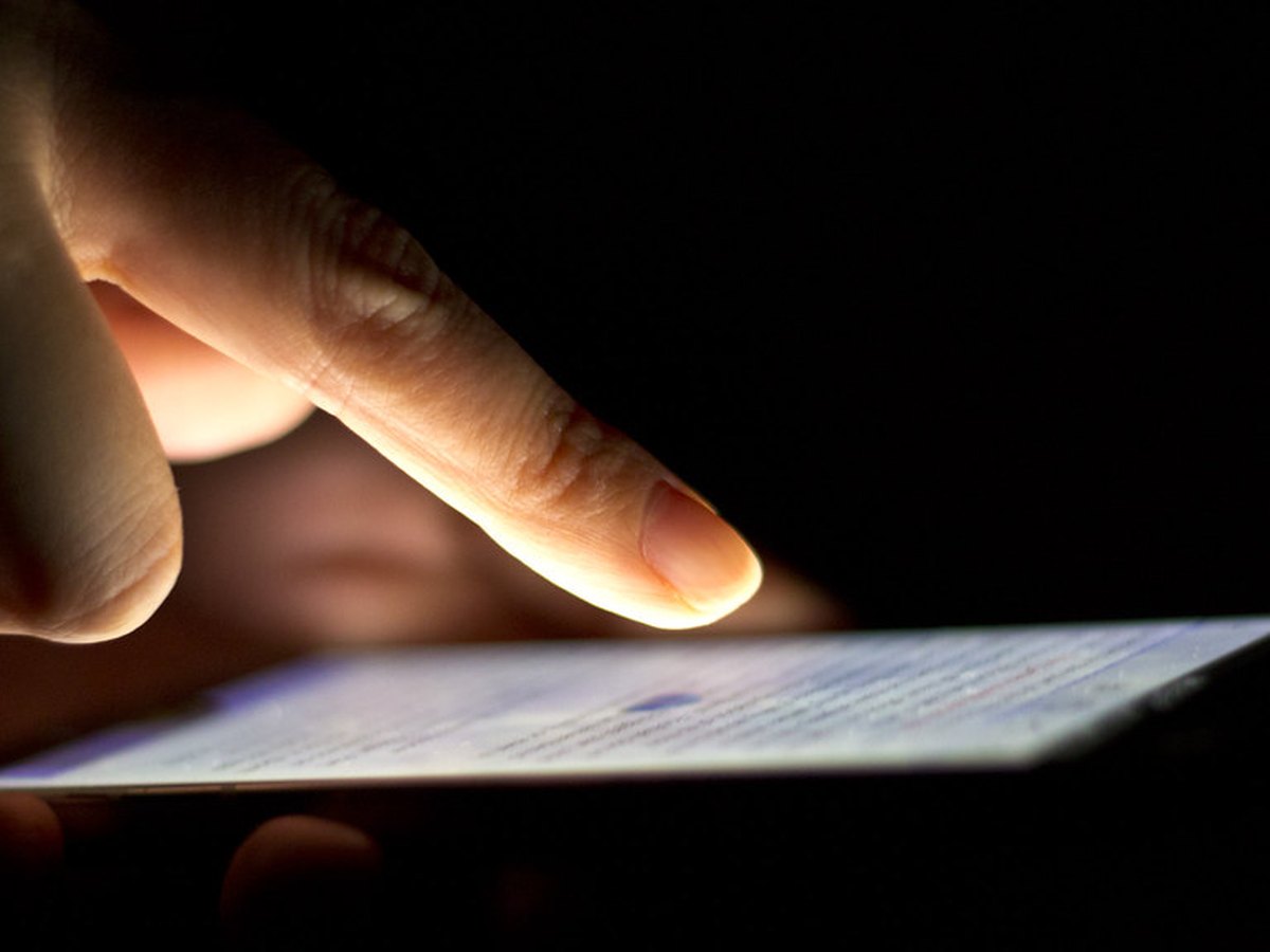 Eine Person spielt ein Quiz am Smartphone, ein Hund liegt daneben